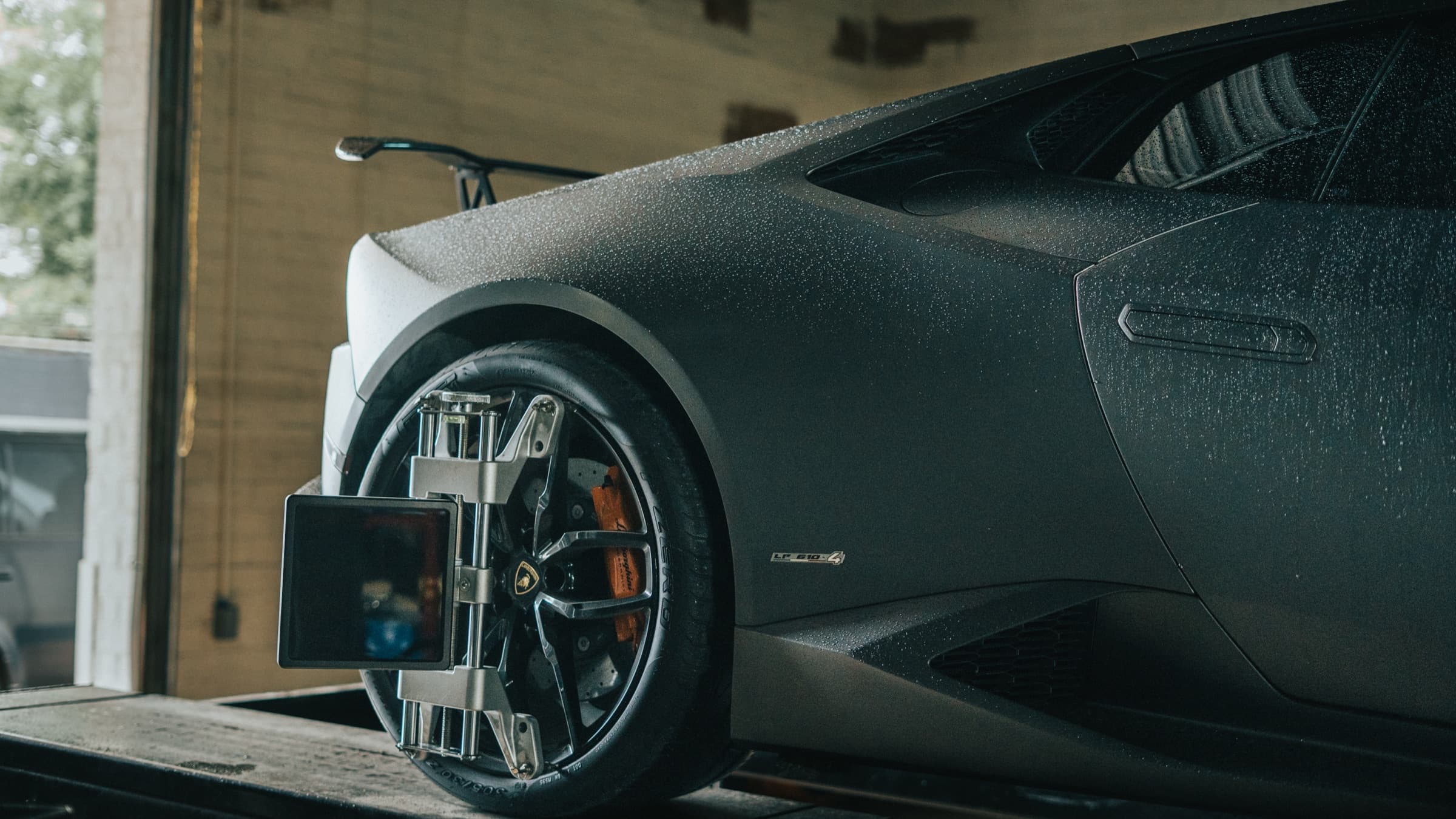 Alignment sensor clamped to the wheel of a Lamborghini Huracán on the rack